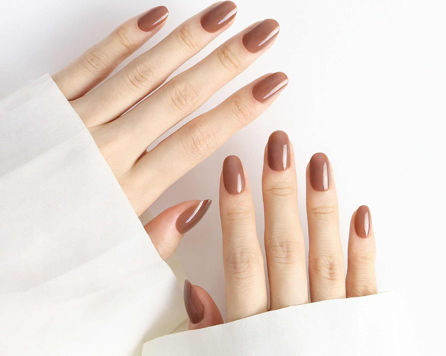 Close-up of a hand with brown nail polish on a white background